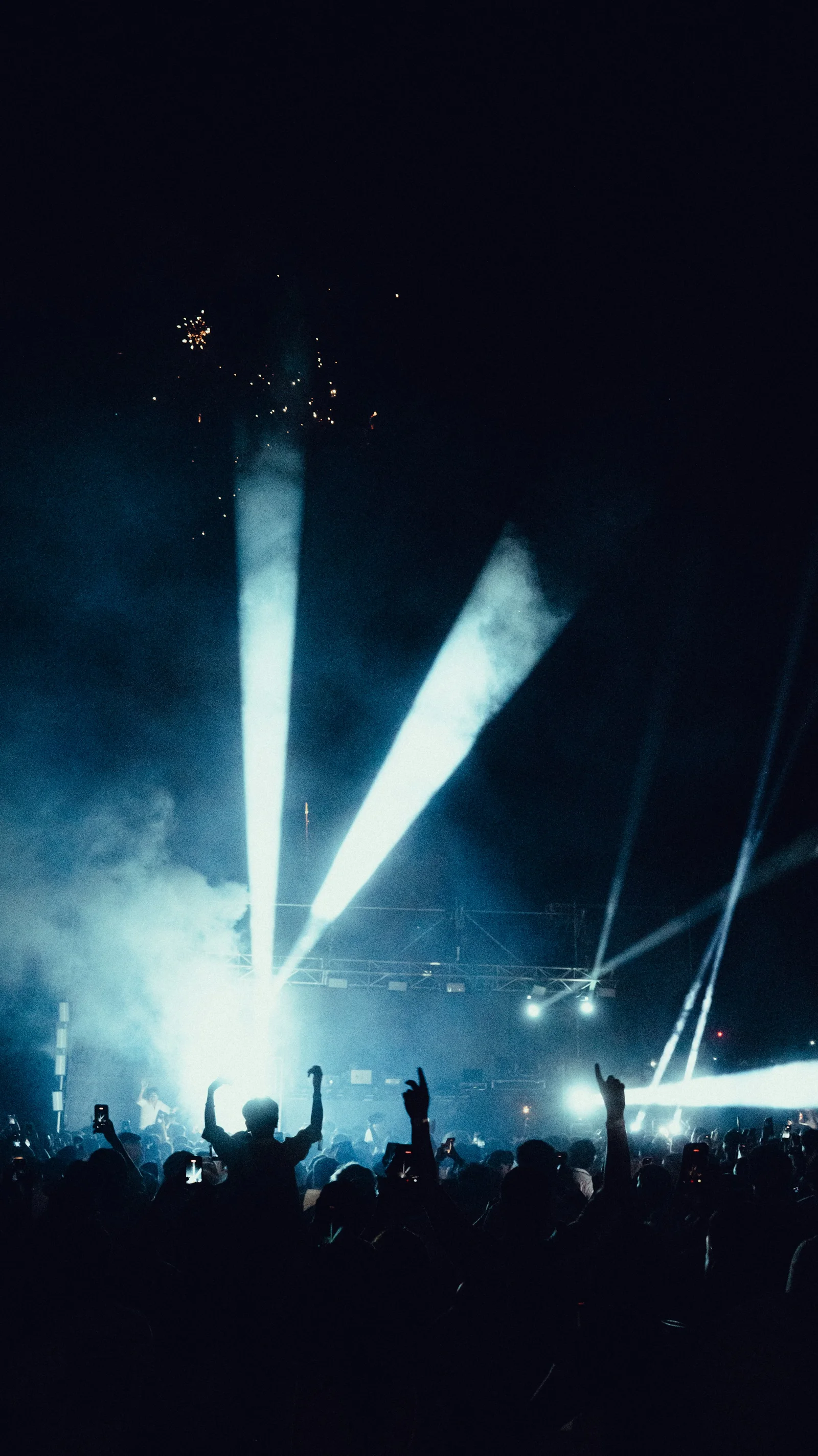 Concert lights rising above an audience in silhouette